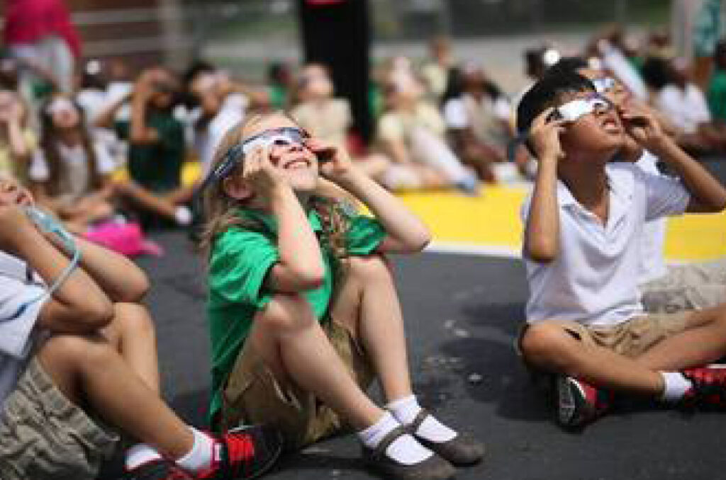 Students looking up through eclipse glasses